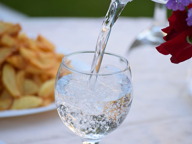 テーブルのグラスに水を注いでいる画像